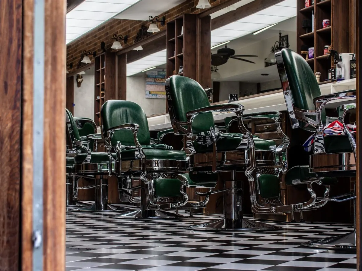 Salão da Barbearia Fernandes, com cadeiras clássicas e piso quadriculado